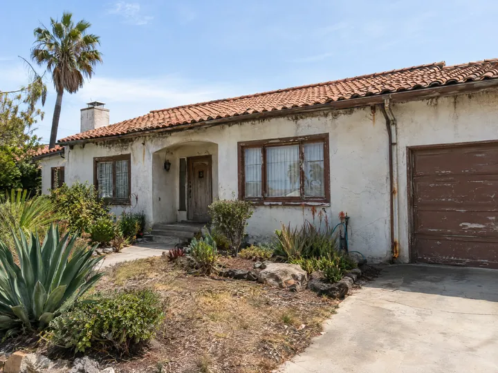 Before: Stucco ranch house with chalky, stained walls and peeling brown trim